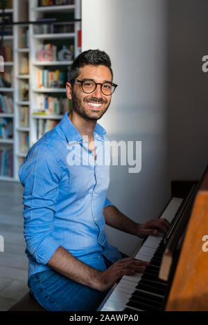 Portrait of happy young man playing piano at home Stock Photo