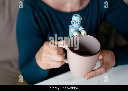 Woman's hands holding mug with little robot Stock Photo