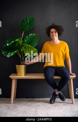 Portrait of young woman holding a house plant and looking to camera Stock Photo
