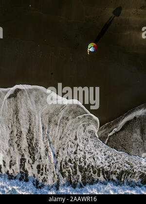 Aerial view of couple unde rainbow colors umbrella at the beach, Kedungu beach, Bali, Indonesia Stock Photo