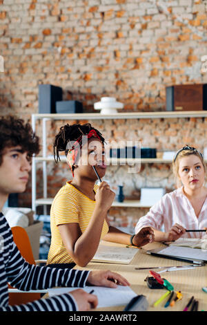 Portrait of young woman in a meeting thinking Stock Photo