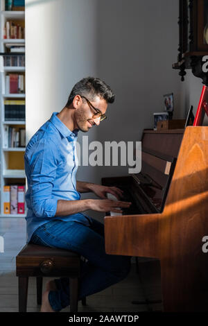 Portrait of smiling young man playing piano at home Stock Photo