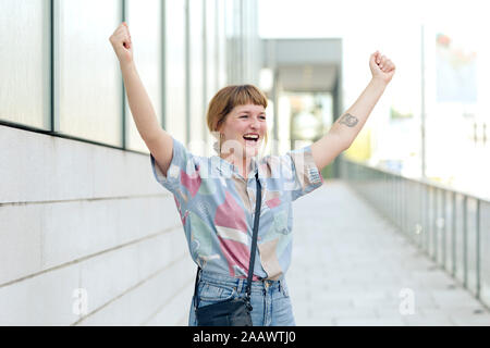 Portrait of happy young woman raising hands Stock Photo