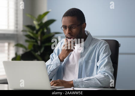Stunned african American man shocked by online news Stock Photo