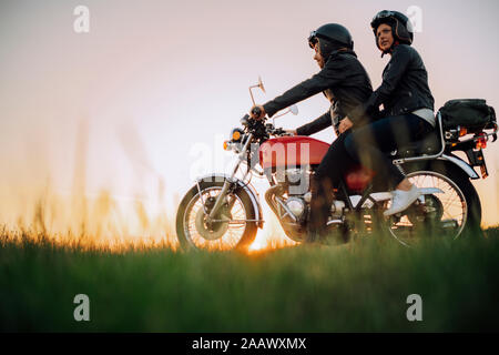 Young couple on vintage motorbike at sunset Stock Photo