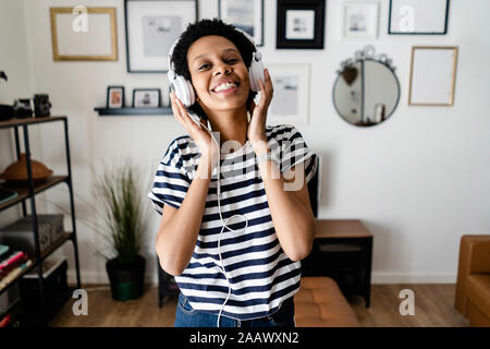 Happy young woman listening to music with headphones at home Stock Photo