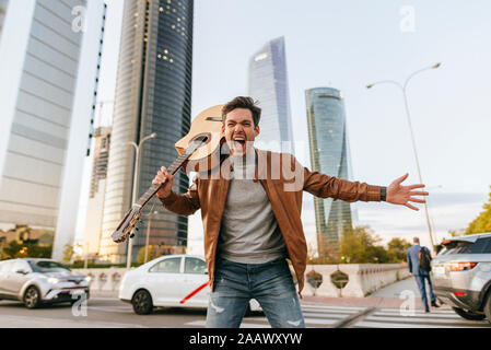 Portrait of screaming man with guitar in the city, Madrid, Spain Stock Photo