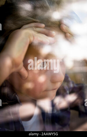 Portrait of girl looking through window Stock Photo