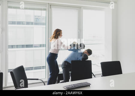 Businesswoman boxing against businessman in office Stock Photo