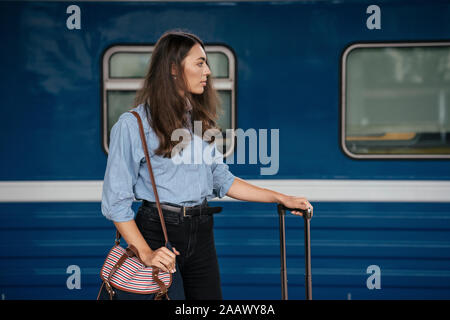 Young female traveller waiting on traing station, looking sideways Stock Photo