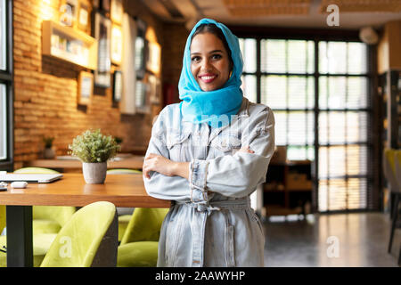 Young woman wearing turquoise hijab in a cafe Stock Photo