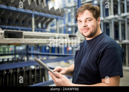 Portrait of confident worker with tablet in factory warehouse Stock Photo