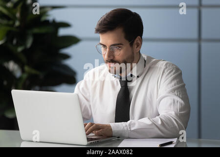 Serious male employee busy using modern laptop in office Stock Photo