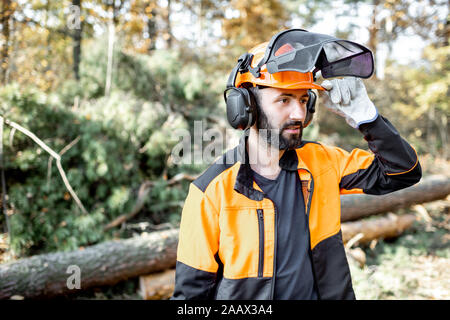 Portrait of a professional lumberman in hardhat and protective clothes working on logging in the pine forest Stock Photo
