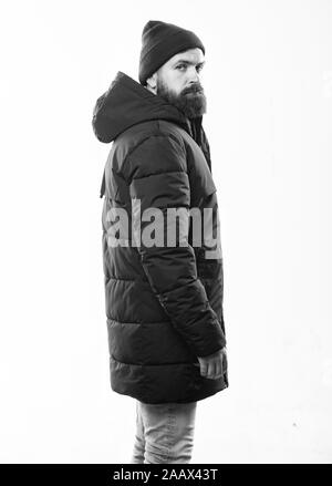 Guy wear hat and black winter jacket. Stylish and comfortable. Hipster  style menswear. Hipster outfit. Man bearded hipster stand in warm black  jacket parka isolated on white. Hipster modern fashion Stock Photo