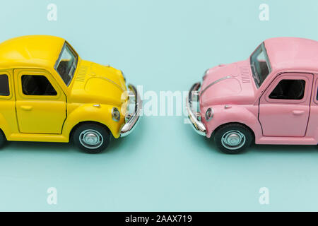 Simply design with two yellow pink vintage retro toy car isolated on blue pastel colorful background. Automobile and transportation symbol. City traffic delivery concept. Copy space for text Stock Photo