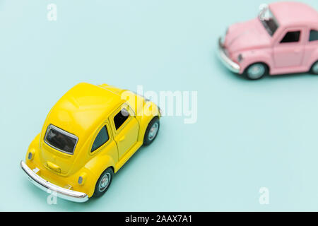 Simply design with two yellow pink vintage retro toy car isolated on blue pastel colorful background. Automobile and transportation symbol. City traffic delivery concept. Copy space for text Stock Photo