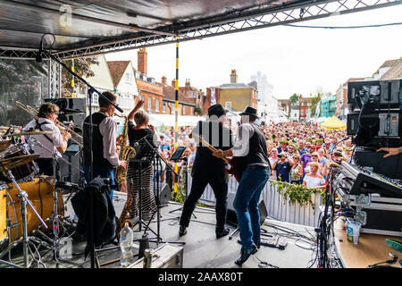 Faversham Hop Festival. Back of stage view of the rock band 'Loose Change' performing concert in front of a packed crowd in the daytime. Stock Photo