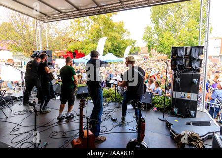 Faversham Hop Festival. Back of stage view of the French rock band 'Sur Les Docks' playing a concert in front of a packed crowd during a sunny day. Stock Photo