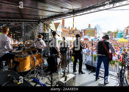 Faversham Hop Festival. Back of stage view of the rock band 'Loose Change' performing concert in front of a packed crowd in the daytime. Stock Photo