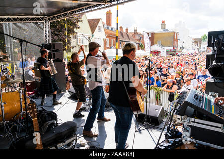 Faversham Hop Festival. Back of stage view of the French rock band 'Sur Les Docks' playing a concert in front of a packed crowd on a summertime day. Stock Photo