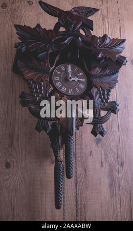 Cuckoo clock hanging on a rustic wooden wall Stock Photo