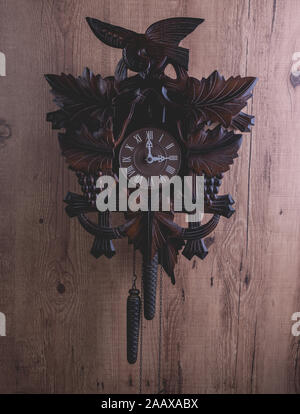 Cuckoo clock hanging on a rustic wooden wall Stock Photo