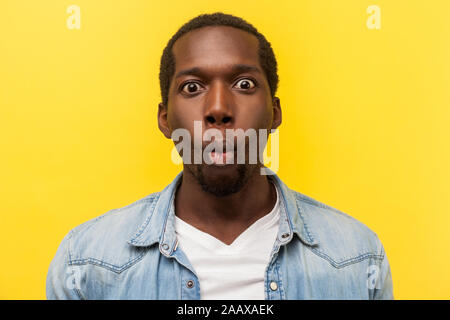 Portrait of excited funny man in denim shirt making fish face with lips and big amazed eyes, looking surprised and silly at camera, wondered expressio Stock Photo