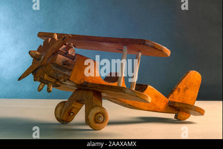 A wooden model biplane aircraft, in a studio setting shot against blue gradiated background Stock Photo