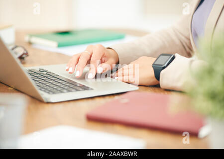 Side view closeup of unrecognizable businesswoman using laptop while working at desk in office, focus on female hands typing on keyboard, copy space Stock Photo