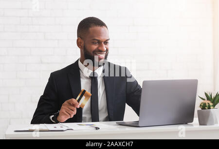 Happy young man holding credit card, making purchases online Stock Photo