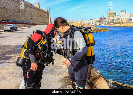 Divers performing a a buddy check prior to diving  the wreck of HMS Maori sun during World War Two in St Elmo's Bay Malta. Stock Photo