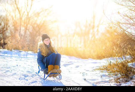 Cute girl sledding in a snowy winter park. Children have fun and have fun. Winter fun. Stock Photo