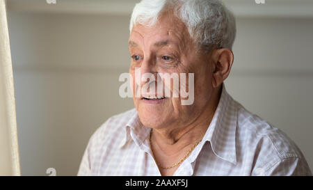 Happy older retired man looking with hope out of window. Stock Photo
