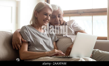 Happy older married couple enjoying spending free time online. Stock Photo