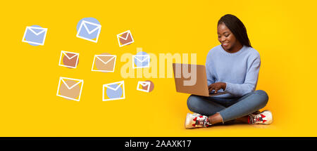Woman typing text message on laptop, flying email envelopes Stock Photo