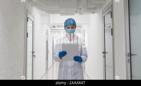 Woman looking at analises on paper and walking through corridor Stock Photo