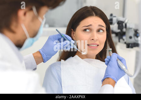 Scared woman at dental office, looking panickly at dentist Stock Photo