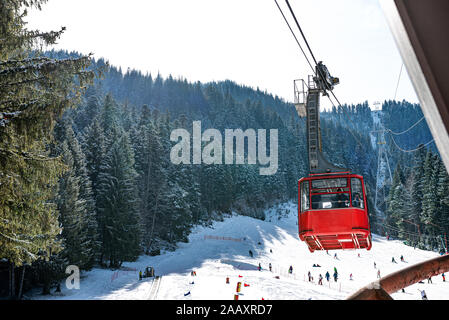 Aerial view of ski slope and red cable car cabin above Poiana Brasov resort in winter season Stock Photo