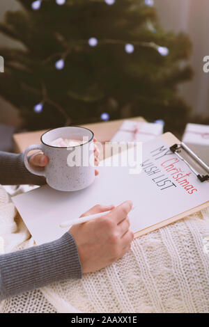 Woman writing wish list for Christmas and sitting at home Stock Photo
