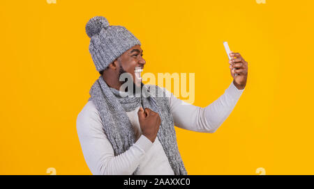 Happy black guy in grey winter hat taking selfie Stock Photo