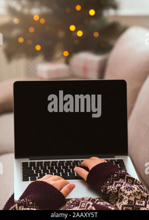 Woman in warm sweater with patterns typing on laptop Stock Photo