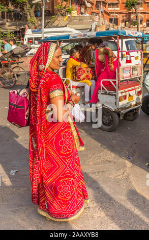 Indian woman in tradtional red dress crossing the street in Jaipur, India Stock Photo