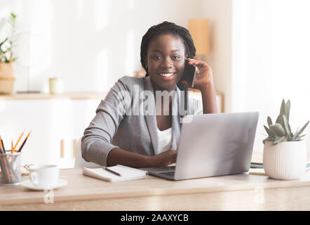 Smiling african female manager talking on cellphone consulting client Stock Photo