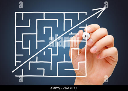 Hand drawing maze shortcut concept with white marker on transparent wipe board over dark blue background. Stock Photo