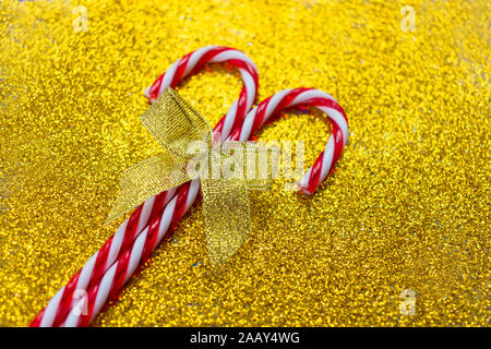 Two christmas candies with a golden bow on a shiny gold background. Stock Photo