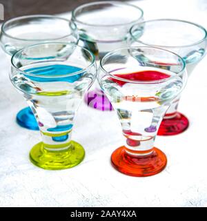 Colorful drinking glasses on white background. Round circuls red, orange, blue green purple neon lights. Stock Photo