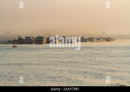 Working boats, in golden evening light, on the banks of the Irrawaddy river, Mandalay, Burma. Copy space for text. Stock Photo