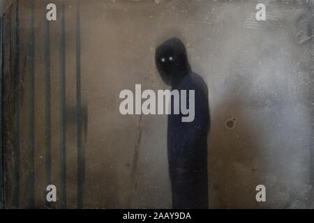 A mysterious spooky hooded figure with glowing eyes standing in a ...