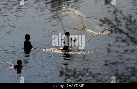 Indigenous Kachok tribe men cast a fishing net in a river near their village in Ratanakiri Province, Canbodia. Stock Photo